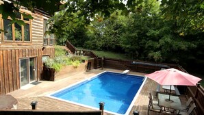 Un jardin avec une piscine, une terrasse en bois et du mobilier d’extérieur.