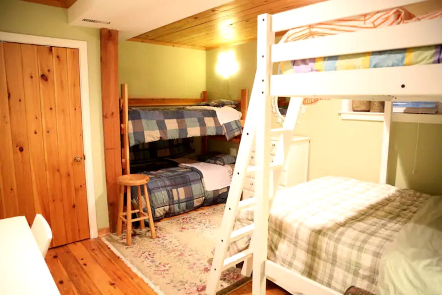 A bunk bed room with a wooden ladder, a small stool, and a door.