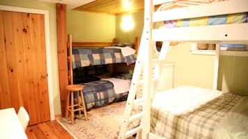 A bunk bed room with a wooden ladder, a small stool, and a door.