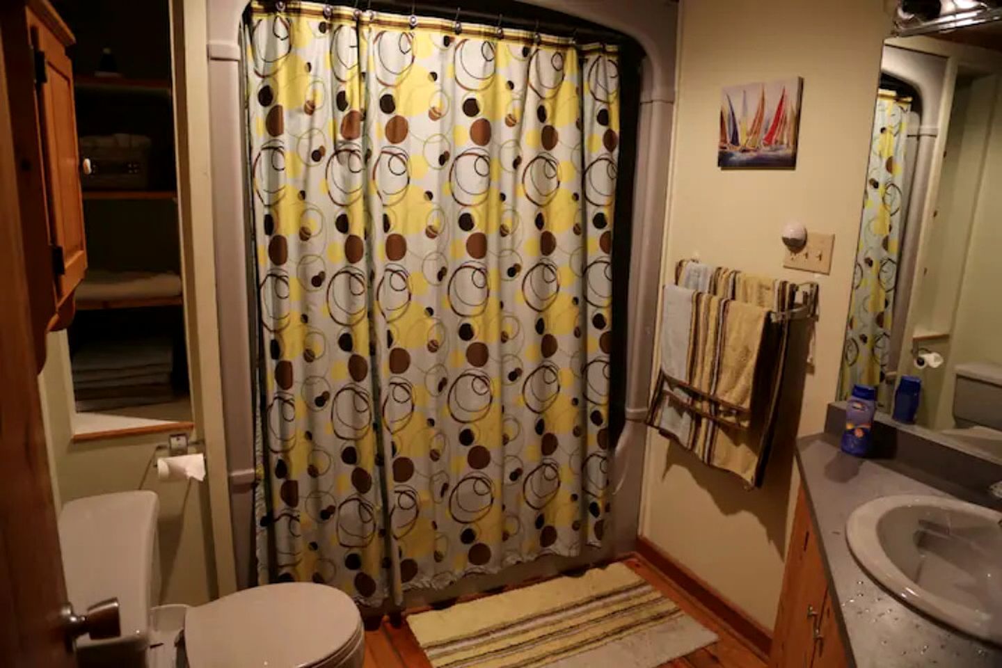 A bathroom with a shower curtain, toilet, sink, and towel rack.