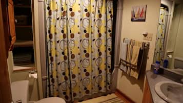 A bathroom with a shower curtain, toilet, sink, and towel rack.