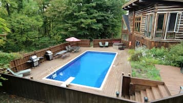 Un jardin avec une piscine, du mobilier de jardin et une terrasse en bois.