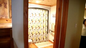 Un intérieur en bois avec un rideau de douche, des toilettes et un plancher en bois.