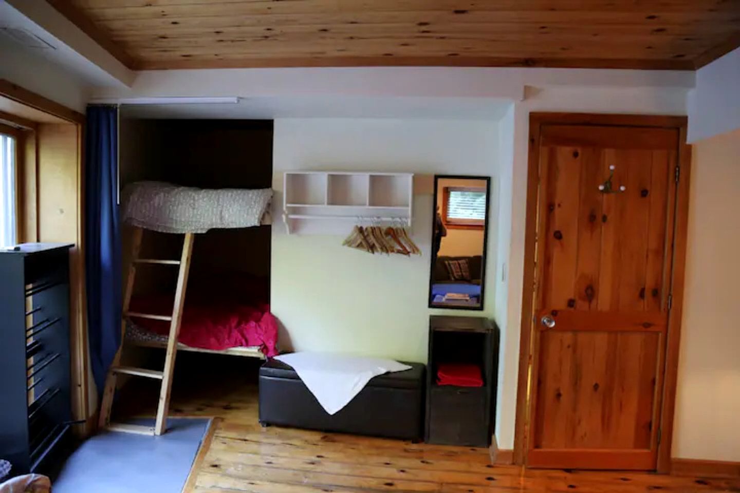 Une chambre avec un lit superposé, un bureau, une armoire et une porte.