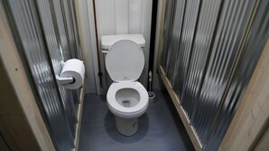 A small, narrow bathroom with a toilet, a toilet paper holder, and a bidet. - Tiny House Rental in Markdale Perfect for a Couple's Retreat in Ontario (Markdale)