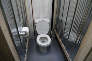 A small, narrow bathroom with a toilet, a toilet paper holder, and a bidet. - Tiny House Rental in Markdale Perfect for a Couple's Retreat in Ontario (Markdale)