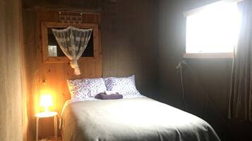 A single bed with a headboard, a bedside lamp, and a window with curtains.