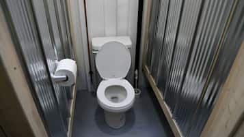 A small, narrow bathroom with a toilet, a toilet paper holder, and a bidet.