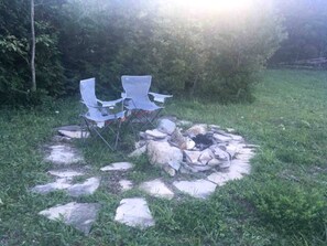 A fire pit with rocks and two folding chairs in a grassy outdoor area. - Tiny House Rental in Markdale Perfect for a Couple's Retreat in Ontario (Markdale)