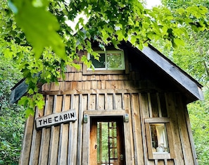 Una cabaña de madera con un letrero que dice 'THE CABIN', una ventana y una puerta.