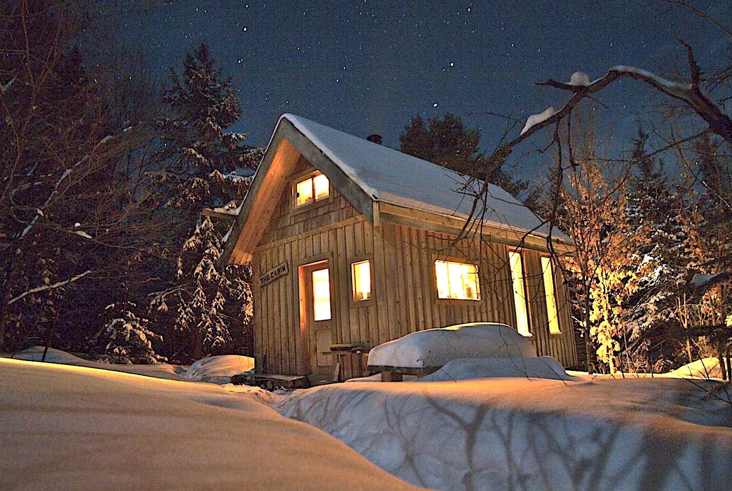 Eine Holzhütte mit schneebedecktem Dach, Holzwänden und einem Fenster mit einem sichtbaren Schild.
