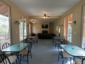 A spacious indoor area with multiple tables and chairs, a fireplace, ceiling fans, and large windows. - Couples Glamping Cabin for Nature Getaway on Golden Lake (Killaloe)