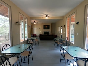 A spacious indoor area with multiple tables and chairs, a fireplace, ceiling fans, and large windows. - Couples Glamping Cabin for Nature Getaway on Golden Lake (Killaloe)