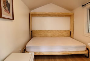 A single bed with a wooden frame in a room with a sloped ceiling and a window. - Golden Lake Glamping Cabin for an Outdoor Adventure in Killaloe, Ontario (Killaloe)