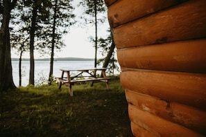 A wooden cabin with a picnic table and a view of a lake. - Golden Lake Glamping Cabin for an Outdoor Adventure in Killaloe, Ontario (Killaloe)
