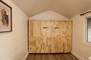 A room with a wooden wardrobe, a framed picture on the wall, and a window with a view. - Golden Lake Glamping Cabin for an Outdoor Adventure in Killaloe, Ontario (Killaloe)