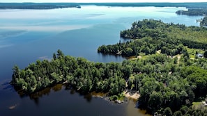An aerial view of a forested island with a lake, surrounded by dense trees and a few buildings. - Golden Lake Glamping Cabin for an Outdoor Adventure in Killaloe, Ontario (Killaloe)
