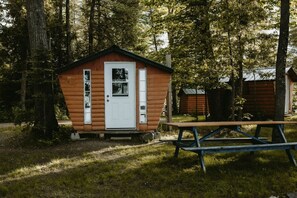 A small wooden cabin with a white door, surrounded by trees. - Golden Lake Glamping Cabin for an Outdoor Adventure in Killaloe, Ontario (Killaloe)