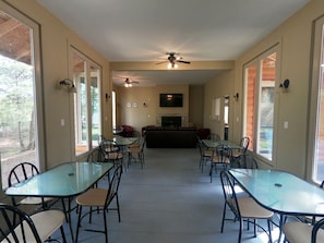 A spacious indoor area with multiple tables and chairs, a fireplace, ceiling fans, and large windows. - Golden Lake Glamping Cabin for an Outdoor Adventure in Killaloe, Ontario (Killaloe)
