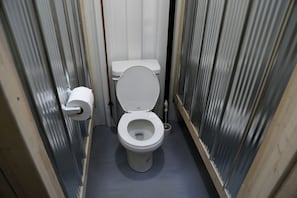 A small, narrow bathroom with a toilet, a toilet paper holder, and a bidet.