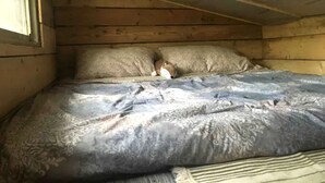 A bedroom with a wooden ceiling, a bed with patterned bedding, and a pillow. - Rural Cabin Surrounded by Beautiful Nature in Ontario (Markdale)