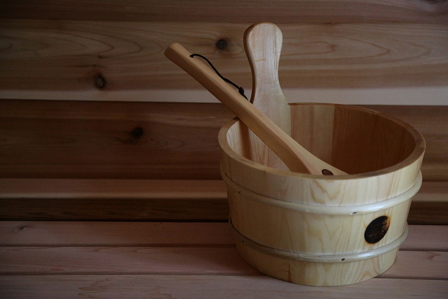 Un balde de madera con una cuchara de madera en su interior, sobre una superficie de madera.