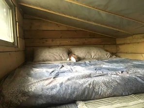 A bedroom with a wooden ceiling, a bed with patterned bedding, and a pillow.