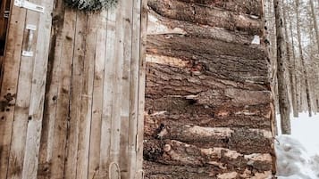 A rustic cabin with a wooden exterior, a wreath on the door, and a basket on the ground.