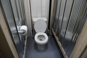 Un baño pequeño y estrecho con un inodoro, un dispensador de papel higiénico y un bidé.