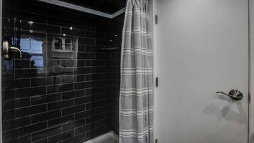 A bathroom with black tiled walls, a white door, and a shower curtain.