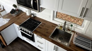 Una cocina moderna con microondas, estufa, fregadero y una ventana con diseño de hojas.