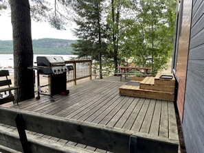 A wooden deck with a grill, wooden steps, and a bench.