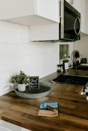 Une cuisine équipée d’un four à micro-ondes, une pancarte sur laquelle on peut lire « Hourra ! Vous êtes là ! », une plante en pot et un livre posé sur le comptoir.
