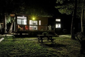 Ein modernes Haus mit einer Terrasse, einem Picknicktisch und einem gut beleuchteten Fenster.