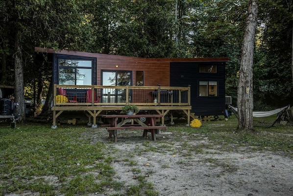 A cabin with a deck, a picnic table, and a hammock.