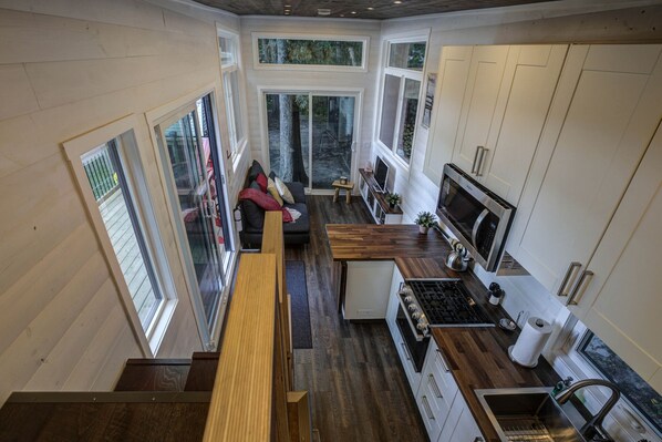 A compact, modern kitchen with a dining area, large windows, and a cozy seating space.