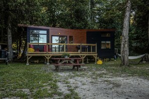 A cabin with a deck, a picnic table, and a hammock.