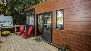 A wooden deck with two red chairs and a potted plant.