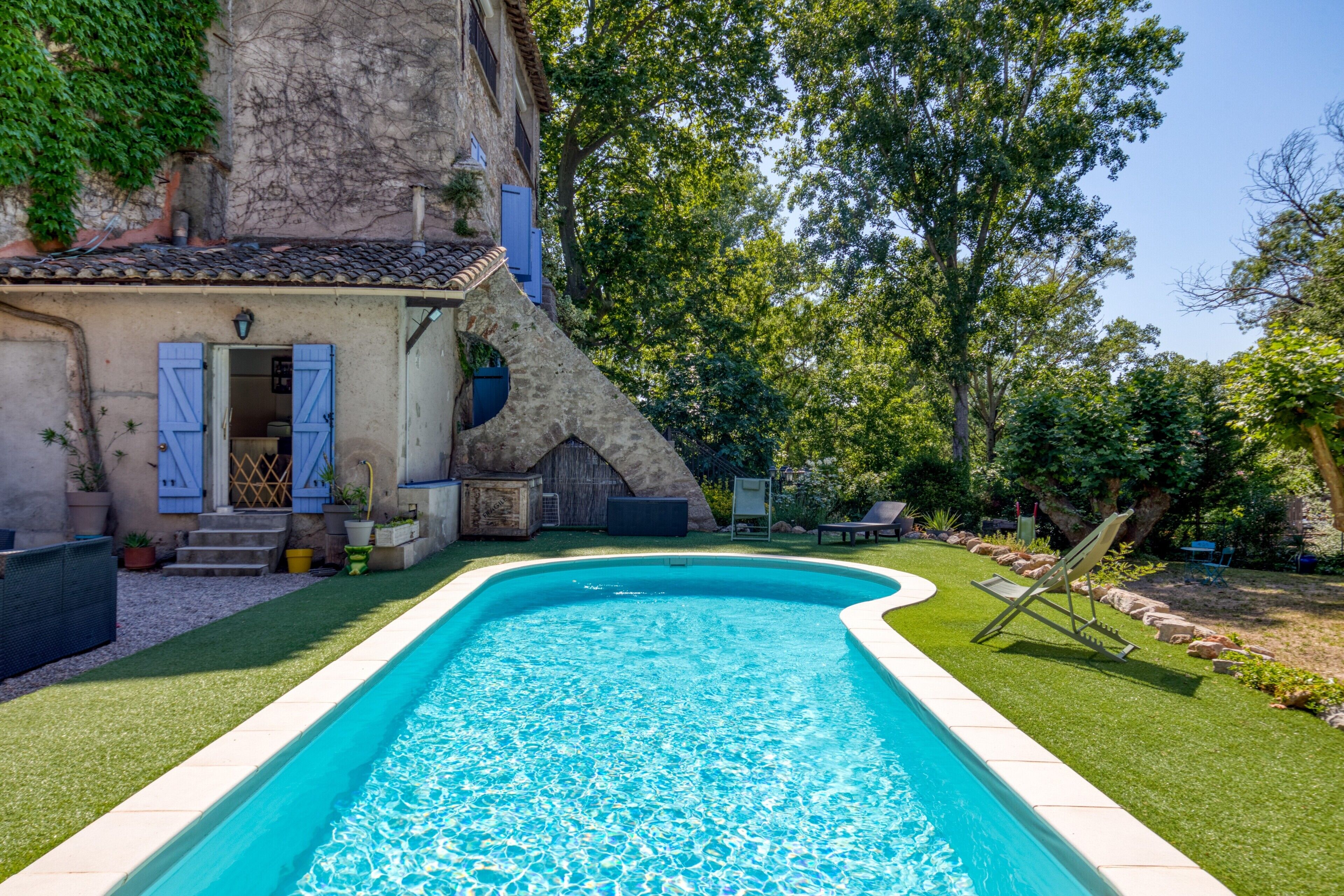 Ein Swimmingpool mit einem Steinhaus und einem Garten.