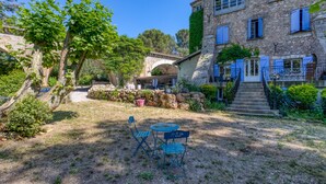 Un edificio de piedra con un patio, mesas al aire libre y una escalera que lleva a la entrada.