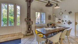 Una cocina con isla central, sillas blancas y una mesa de comedor.