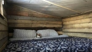 A wooden cabin bedroom with a bed, pillows, and a blanket. - Quaint Off-Grid Cabin with Fire Pit Space in Ontario (Markdale)