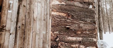 A rustic cabin with a wooden exterior, a wreath on the door, and a basket on the ground.