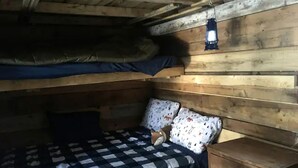 A cabin with a bunk bed, a wooden nightstand, and a lantern. - Quaint Off-Grid Cabin with Fire Pit Space in Ontario (Markdale)
