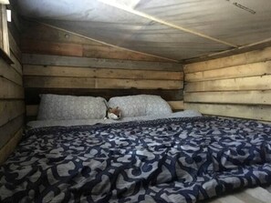 Un dormitorio de cabaña de madera con cama, almohadas y manta.