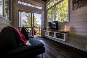 A cozy living room with a dark sofa, a flat-screen TV, and a fireplace.