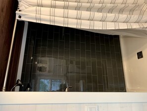 Un baño con pared de azulejos, zona de ducha y cortina.