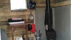 Ein rustikales Holzhaus-Interieur mit einem Holztisch, einem Herd und einem Fenster.