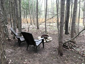A forested area with a bench and a fire pit.