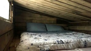 A small, single-bed room with a wooden ceiling and walls, a mattress with a patterned cover, and a window on the left side. - Rustic Cabin Incredible for Hiking and Outdoor Lovers in Ontario (Markdale)